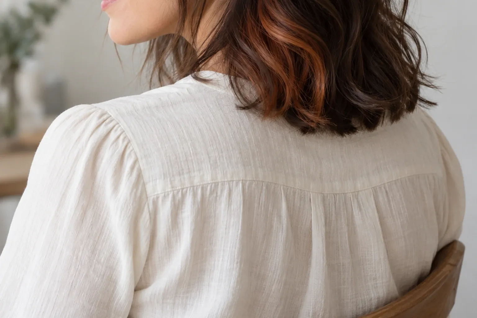 Shoulder-length brown hair with subtle copper peekaboo highlights on a woman turning away